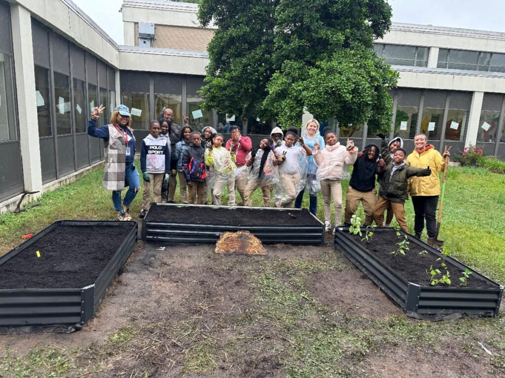 students pose near new raised beds they just built at their schools