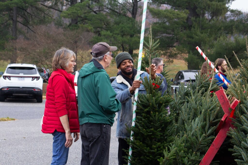 Christin, a FONA staff person, helps visitors select a christmas tree during the annual christmas tree sale.